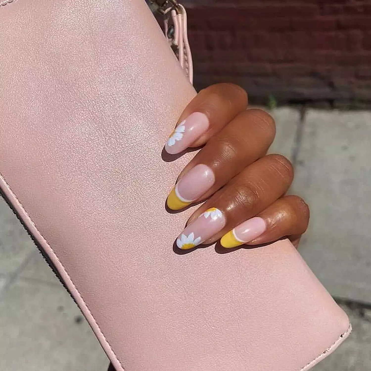 Manicure with pale pink base, yellow French tips, and white and yellow floral designs