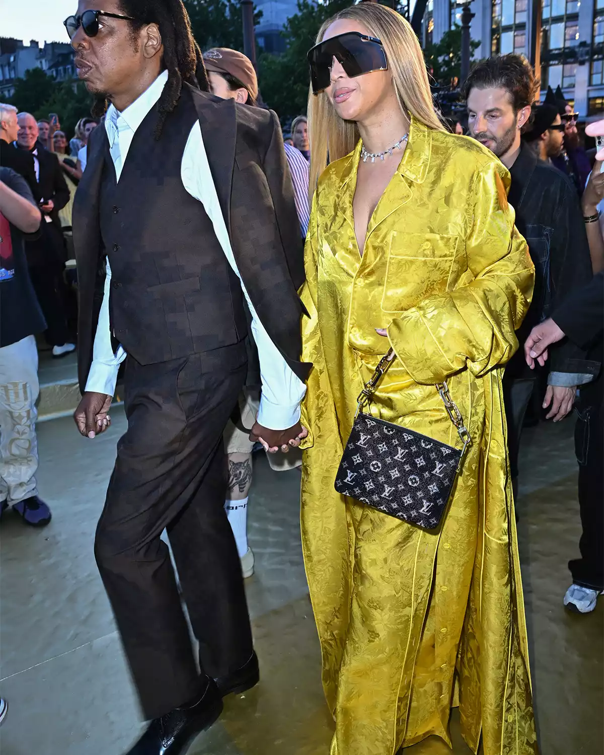 Beyonce wearing a yellow pant suit and holding Jay Z's hand